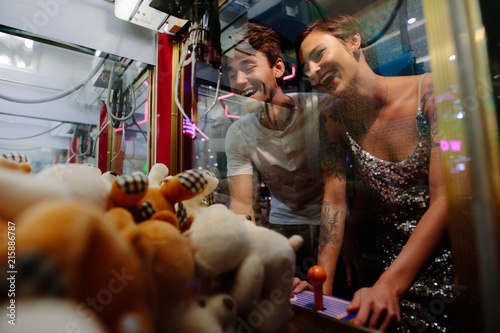 Schilderij op canvas Couple playing games at a gaming arcade