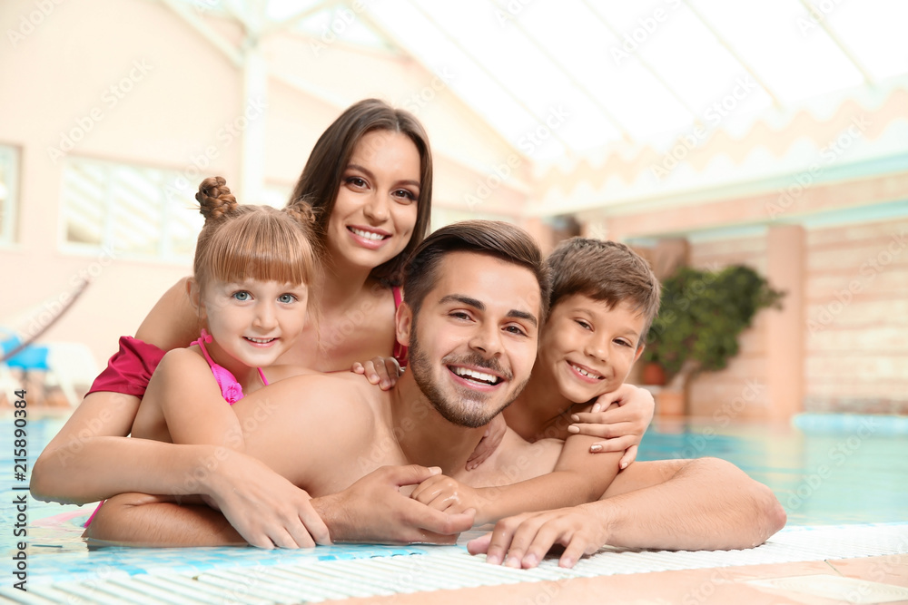 Naklejka premium Happy family resting in indoor swimming pool