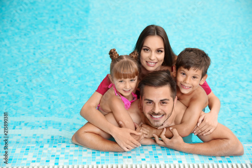 Happy family resting in swimming pool with refreshing water