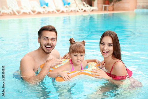 Happy family with inflatable ring in swimming pool