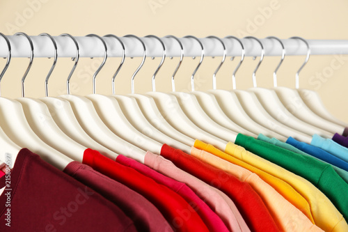 Many t-shirts hanging in order of rainbow colors, closeup
