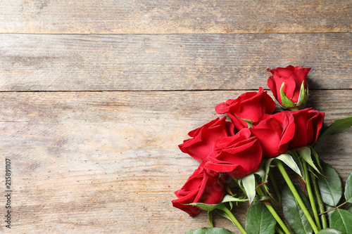Fototapeta Naklejka Na Ścianę i Meble -  Beautiful red rose flowers on wooden background, top view