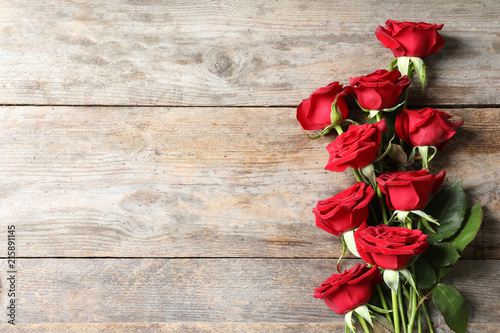 Fototapeta Naklejka Na Ścianę i Meble -  Beautiful red rose flowers on wooden background, top view