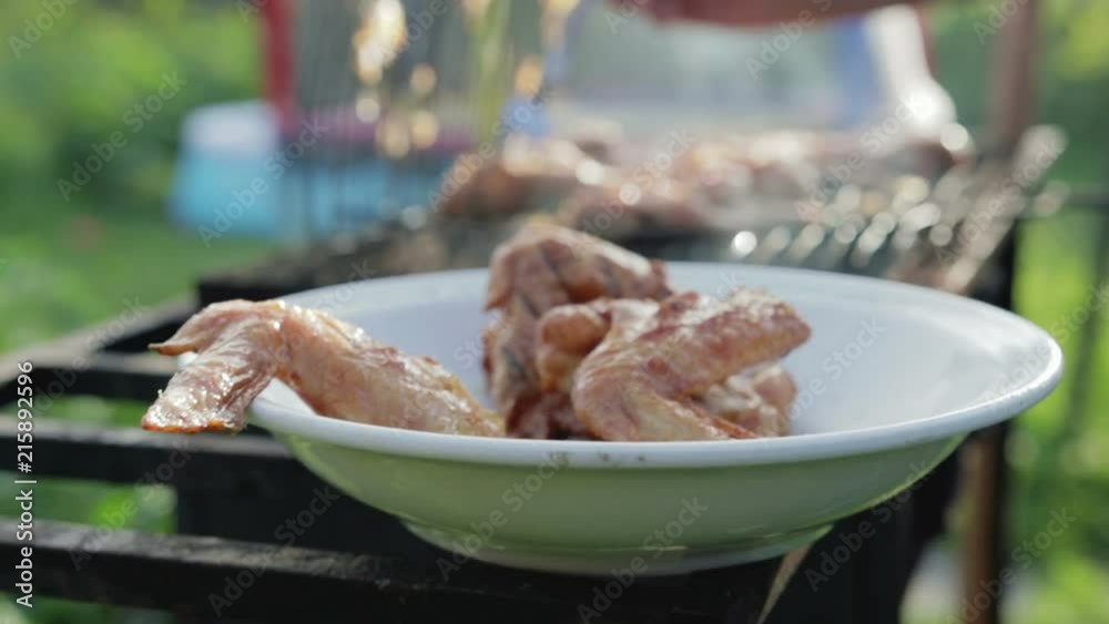 Girl takes off the ready chicken wings from the grill and puts it in a plate Girl takes off the ready chicken wings from the grill and puts it in a plate