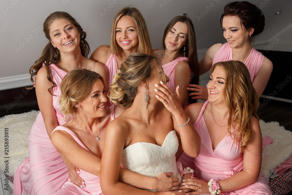 Obraz premium Bride and bridesmaids in pink dresses having fun at wedding day. Happy marriage and wedding party concept