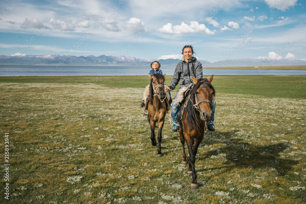 mother and son riding on horses beside a lake mother and son riding on horses beside a lake