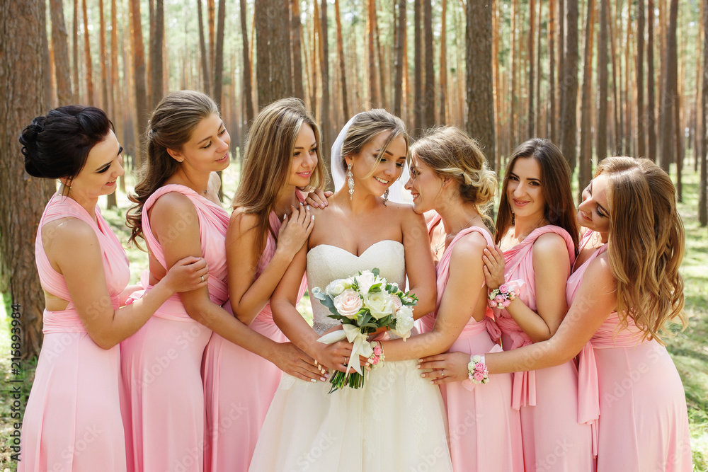 Bride and bridesmaids in pink dresses having fun at wedding day. Happy marriage and wedding party concept