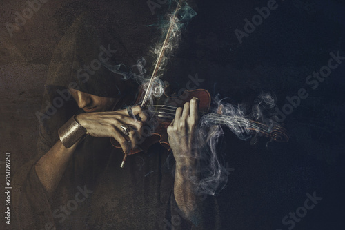 Dark phantom violin player, man performing a concert shrouded in smoke and fog