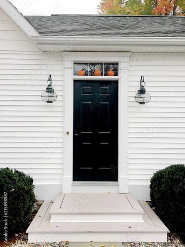 Three tiny pumpkins decorate a front door.