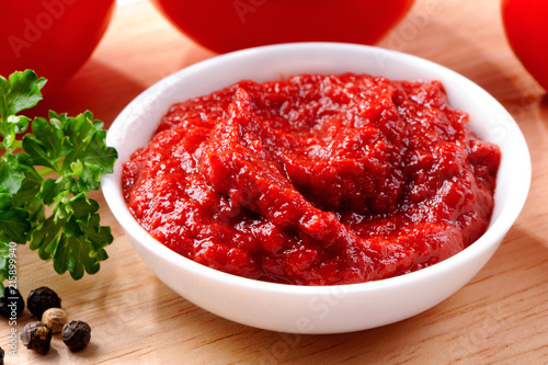 Foto bowl of tomato paste close-up with parsley leaves, tomatoes and peas of black pe