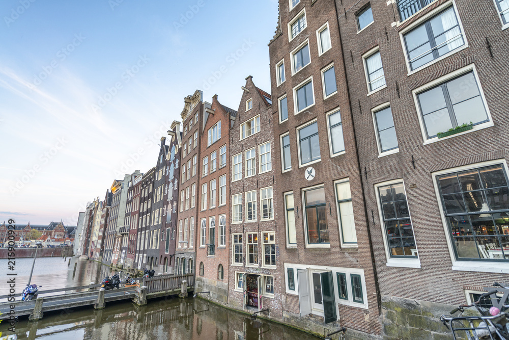 AMSTERDAM, THE NETHERLANDS - MARCH 2015: View of city buildings along canal. The city hosts 15 million tourists annually