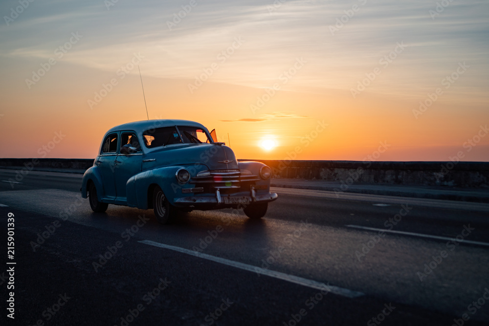 Blue Vintage American Car in Havana Cuba during Sunset on Malecon Highway with Sea Wall next to the Ocean.