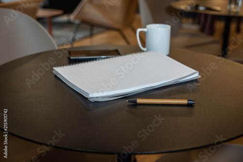 Pen on a round desk with note pad and coffee mug