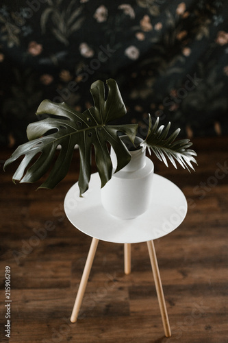 large green leaves in vase on round end table on hardwood floor