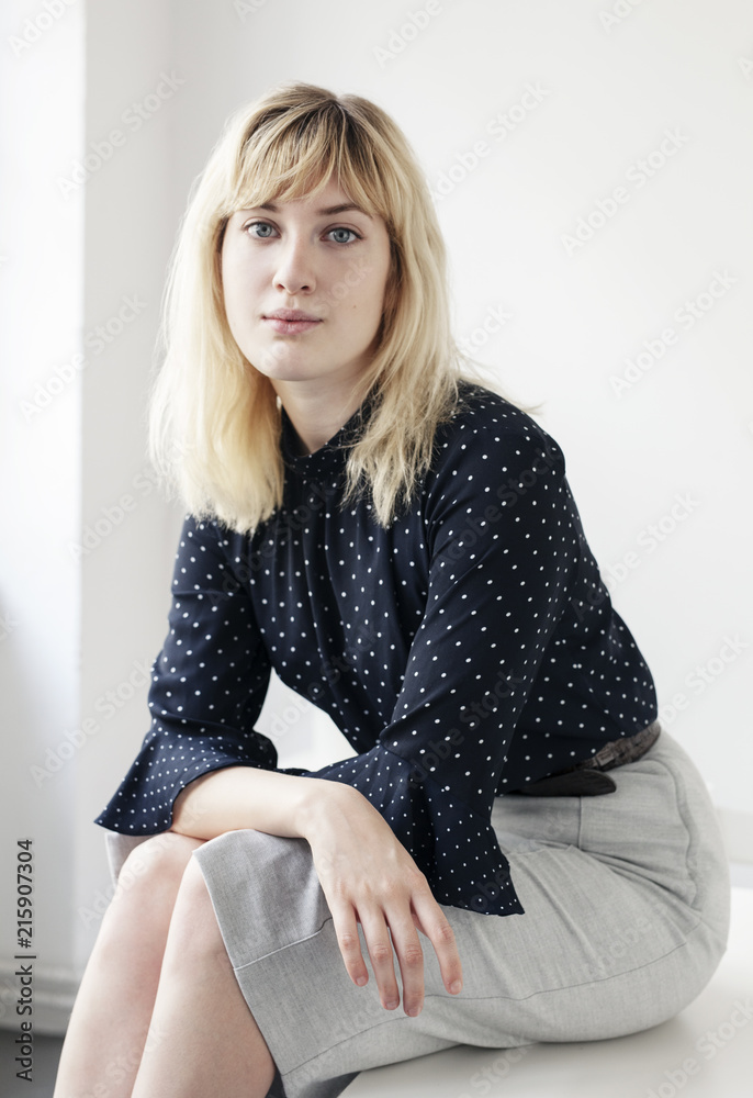 A relaxed portrait of a young blonde woman sitting on a desk. A relaxed portrait of a young blonde woman sitting on a desk.