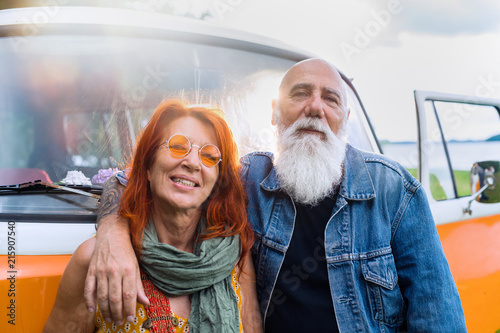 An old hipster couple posing in front of their camper van 