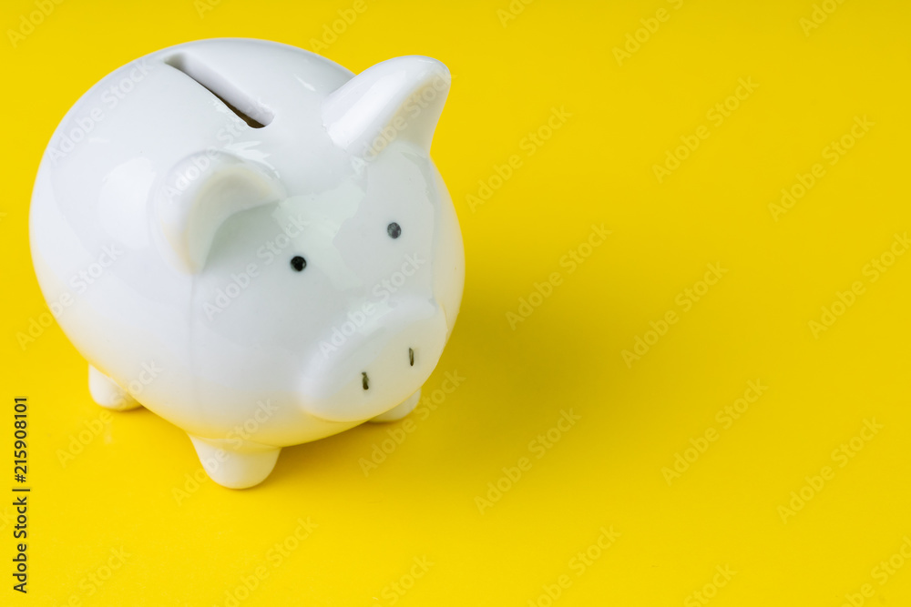 Financial, savings, budget, cost or investment concept, white happy piggy bank on vivid yellow background with copy space Financial, savings, budget, cost or investment concept, white happy piggy bank on vivid yellow background with copy space