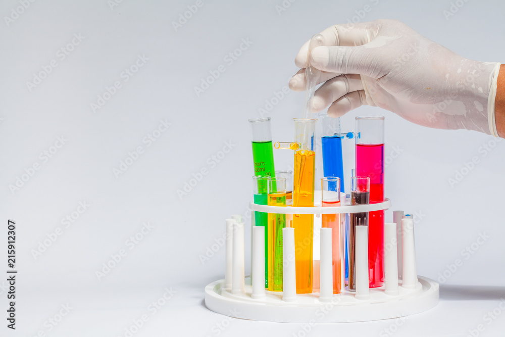 Experiments in mixing chemical substances into glass tubes with a microscope in a science lab with a white background.. Experiments in mixing chemical substances into glass tubes with a microscope in a science lab with a white background..