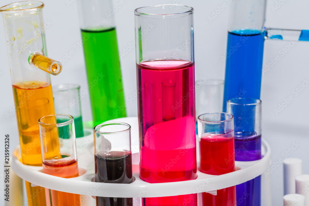 Experiments in mixing chemical substances into glass tubes with a microscope in a science lab with a white background.. Experiments in mixing chemical substances into glass tubes with a microscope in a science lab with a white background..