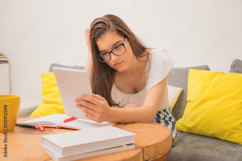 Cute teenager girl using digital tablet while sitting on the couch at home. Cute teenager girl using digital tablet while sitting on the couch at home.