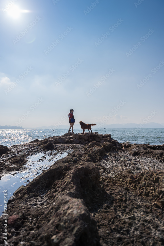 Golden retriever and Girl on the rocks by the sea