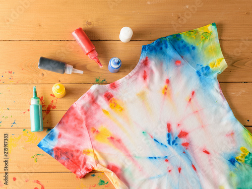 T-shirt painted in tie dye style on a brown wooden table.