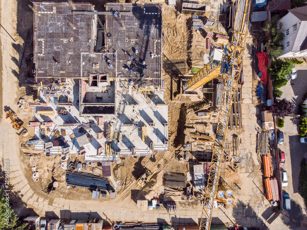 yellow tower cranes near multilevel concrete building under construction. drone photo of civil construction site