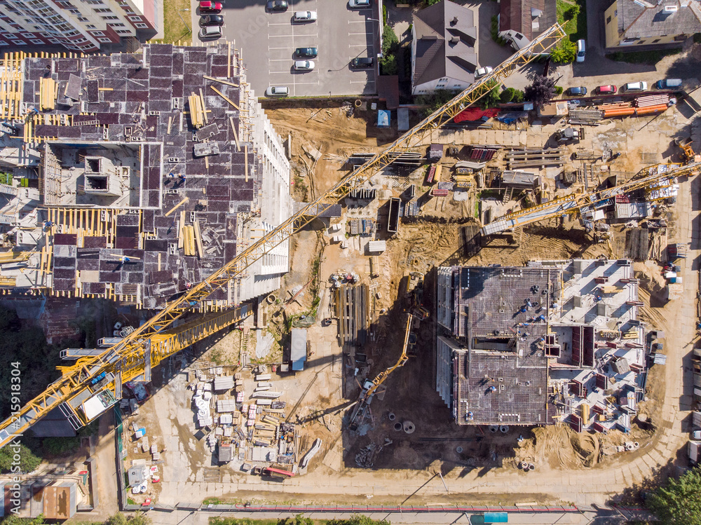two tower cranes and other construction machines working at building site. aerial photo