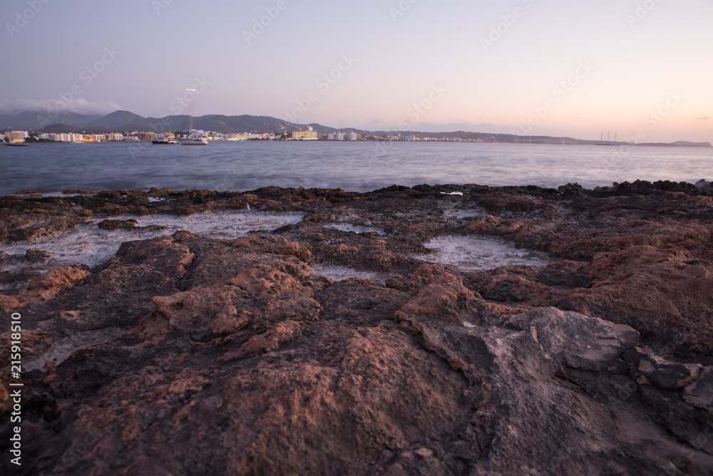 Ibiza sunset with rocks and basalt salt water over the Mediterranean coast 