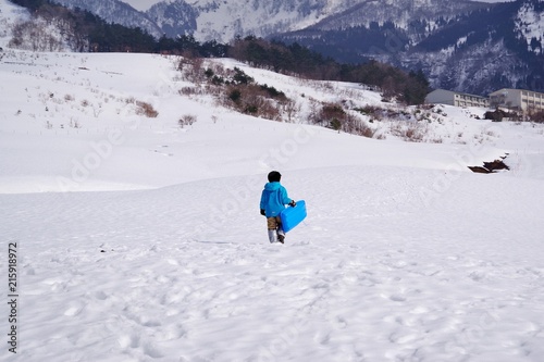 雪山でソリ遊びをする子供