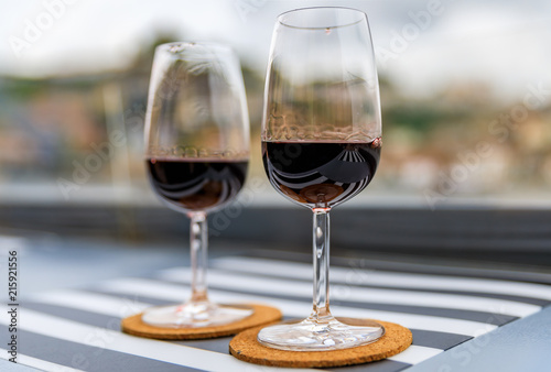 Glasses of port wine at an outdoor restaurant with the Douro river and Dom Luis I bridge blurred in the background in Porto, Portugal