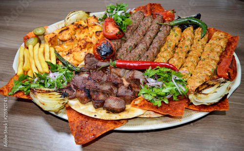 Fast food. Eastern food. Shish kebab, lyulya-kebab, shaverma, pita gyros. Dishes of oriental cuisine lying on pita bread and decorated with greens and vegetables, sauces and French fries.
