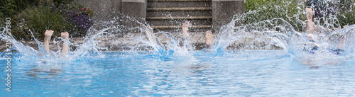 Feet from the surface and splashing water jumping people in the pool. © lapis2380