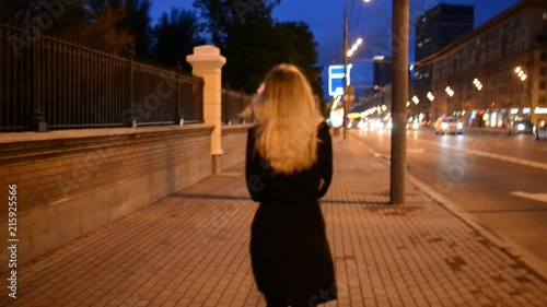 Young woman by the street at night. Handheld footage. High ISO.