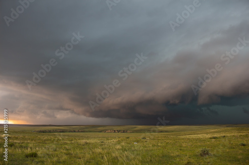 A severe thunderstorm approaches over the great plains landscape. The early evening sun casts an eerie light.
