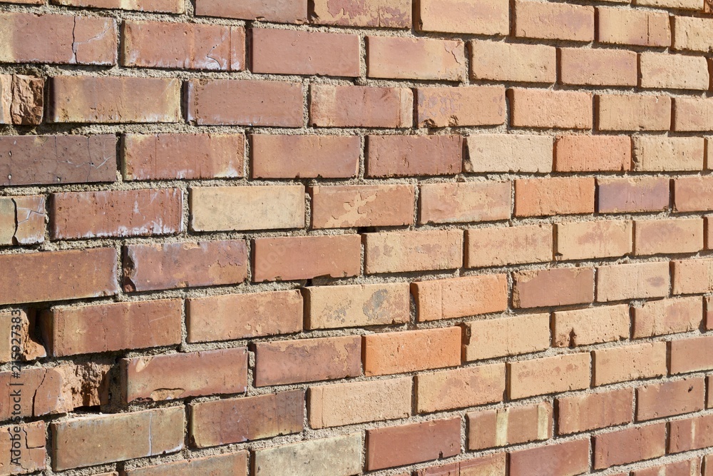 Obraz premium Decomposing brick wall has interesting old bricks in varying hues of brown and tan