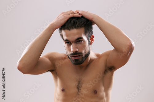 Young man is applying hair gel to his hair. 