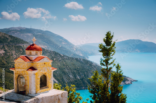 Colorful shrine Proskinitari on pedestal. Amazing sea view to Greece coastline in the background photo