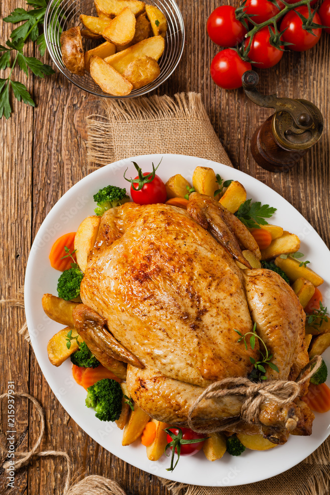 Roast chicken whole. Served on a plate with vegetables and baked potatoes. Roast chicken whole. Served on a plate with vegetables and baked potatoes.