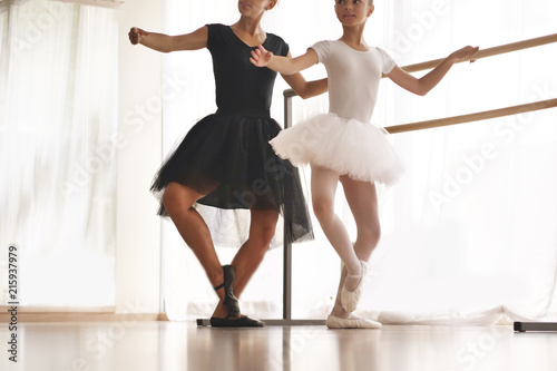 Foto A teacher of classical dance teaches some steps to his young student who wants to learn how to dance and in the background the other little girls who listen