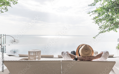 Relaxation holiday vacation of businessman take it easy resting on beach chair at swimming pool poolside beachfront resort hotel with sea or ocean view and summer sunny sky