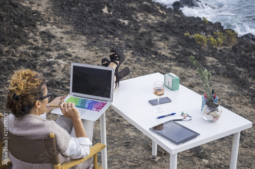 alternative office business place for elegant manager woman caucasian working with technology modern laptop just in front of the ocean. phone and tablet on the desktop with ocean view. workstation photo