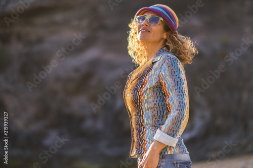 Fototapeta Naklejka Na Ścianę i Meble -  cheerful happy attractive middle age caucasian woman smile and look in the air enjoying the nice weather and the sun. happiness in outdoor leisure activity and coloured dress like hippy