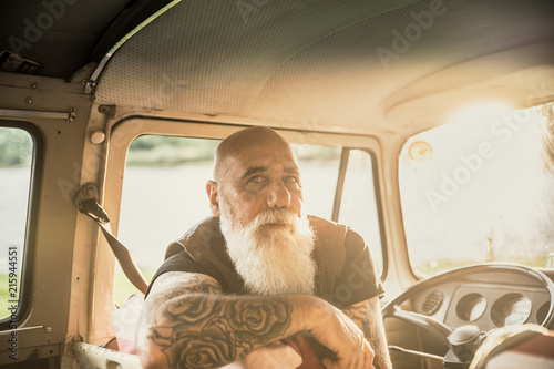 Portrait of a senior hipster inside their vintage van 