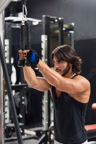 Young man exercising triceps pulldown at the gym