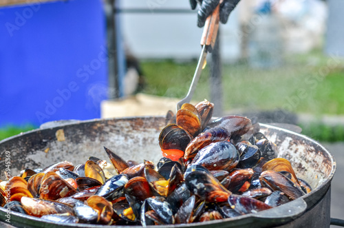 Fresh mussels roasted on a grill pan. Seafood cooked outdoors. Selective focus