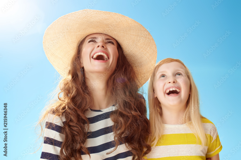 smiling mother and child looking at copy space against blue sky