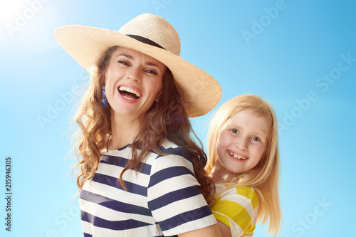 smiling modern mother and child hugging against blue sky