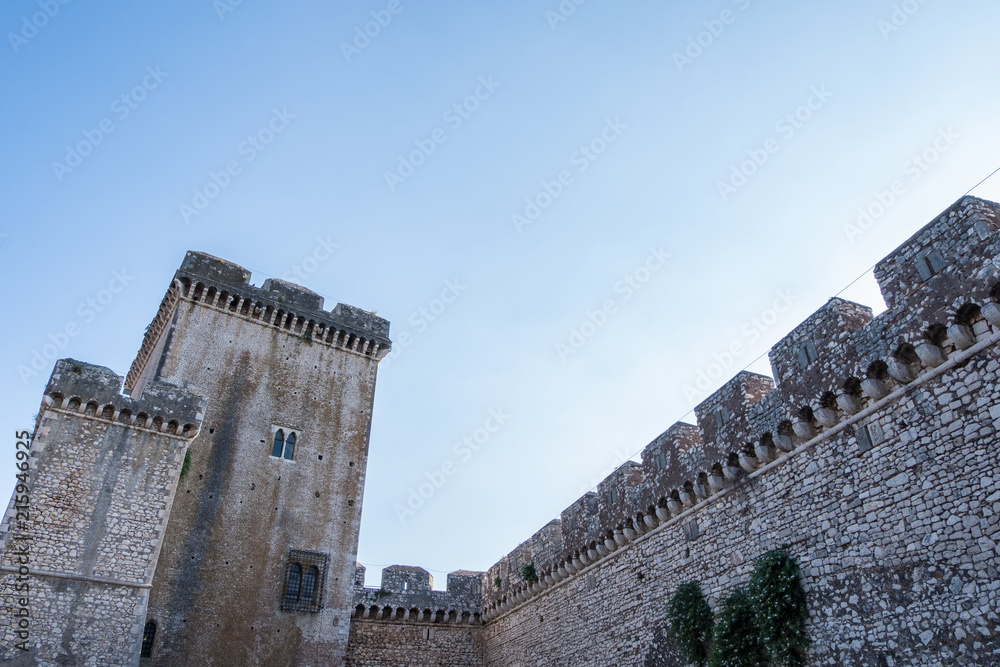 Walls and tower of ancient castle with clouds and blue sky background.