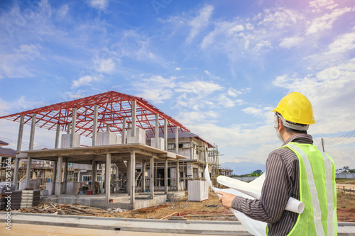 Professional engineer architect worker with protective helmet and blueprints paper at house building construction site © Kwangmoozaa